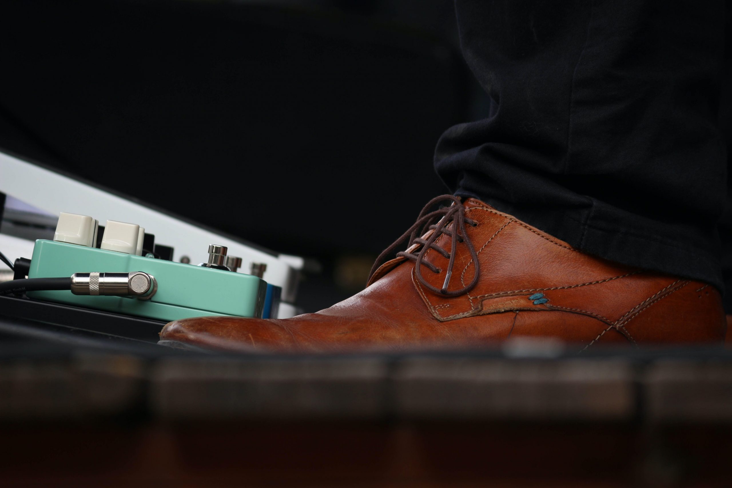 Man's Boot in front of pedalboard