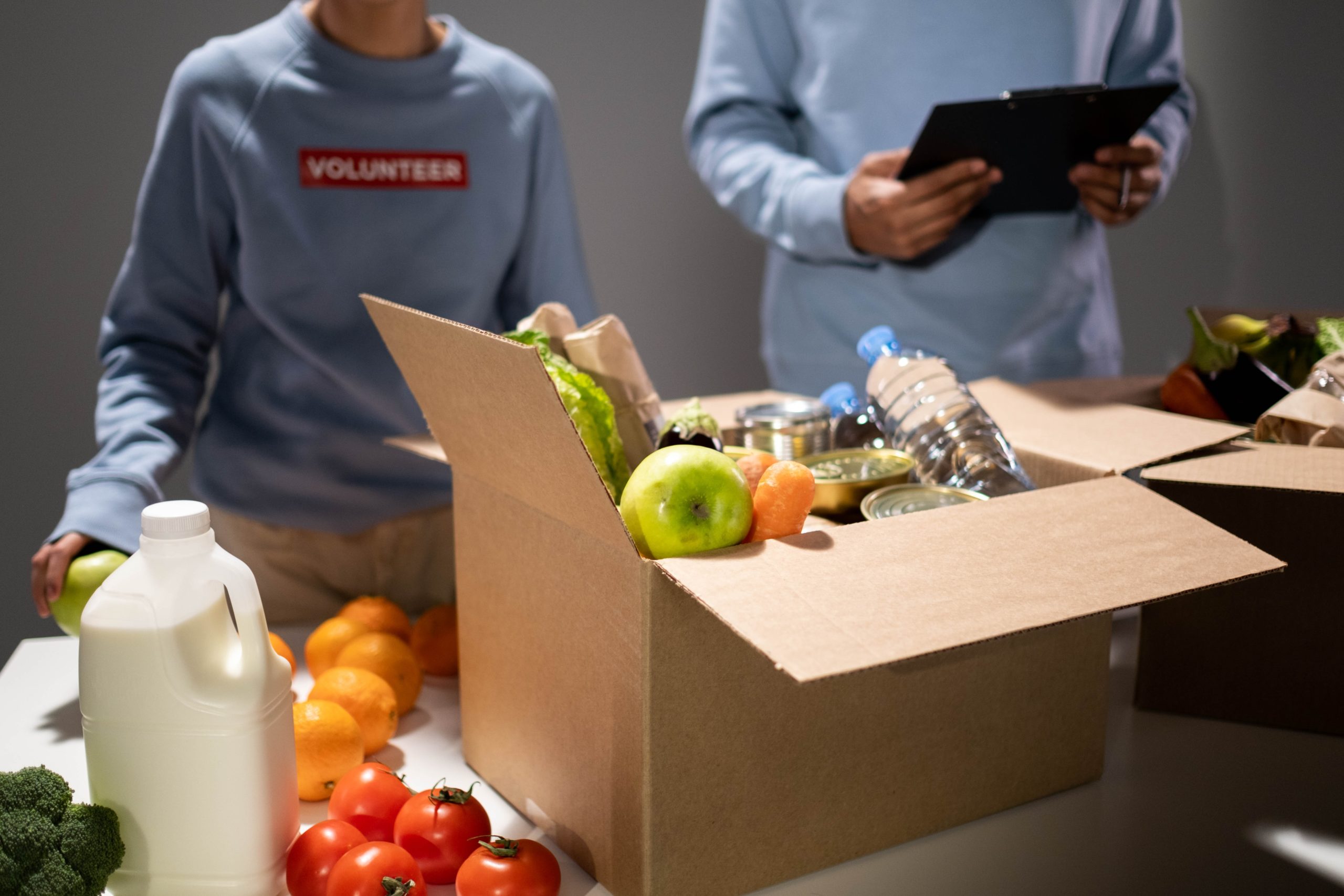 Food charity drive with volunteers collecting groceries in a box
